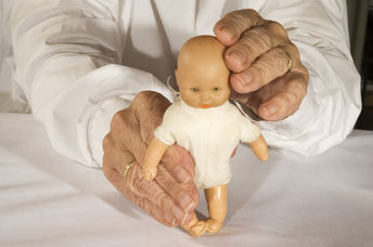 Old demented person plays with toy doll