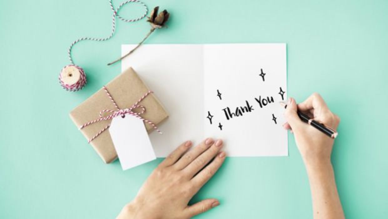 A woman writes thank you on a card A woman writes thank you on a card