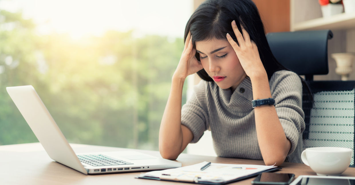 A young woman sits at her desk with a headache A young woman sits at her desk with a headache