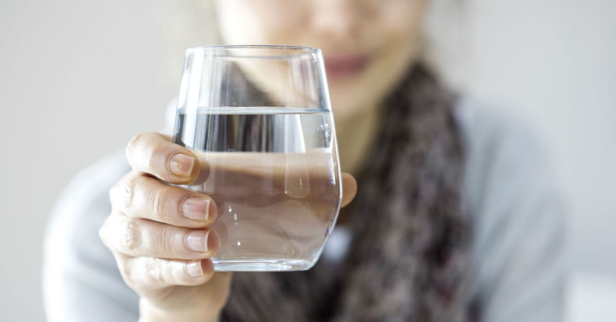 A young woman holding a glass of water. A young woman holding a glass of water.