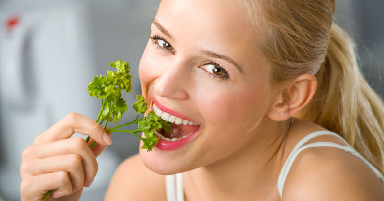 A woman eats a sprig of parsley. A woman eats a sprig of parsley.