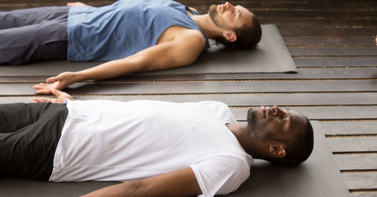 Men in the corpse pose during a yoga class. Men in the corpse pose during a yoga class.