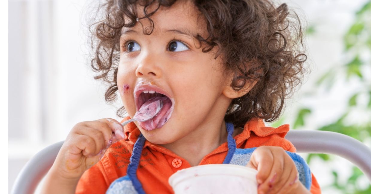 Toddler eating yogurt. Toddler eating yogurt.