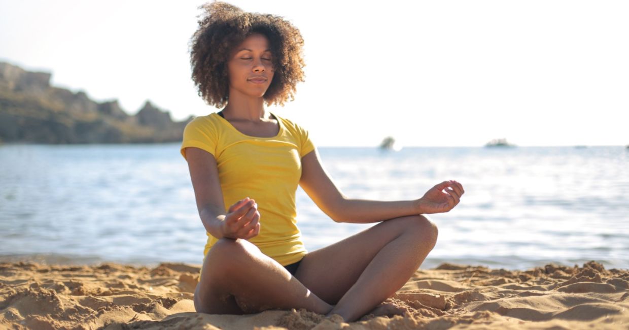 Doing yoga on a beach.