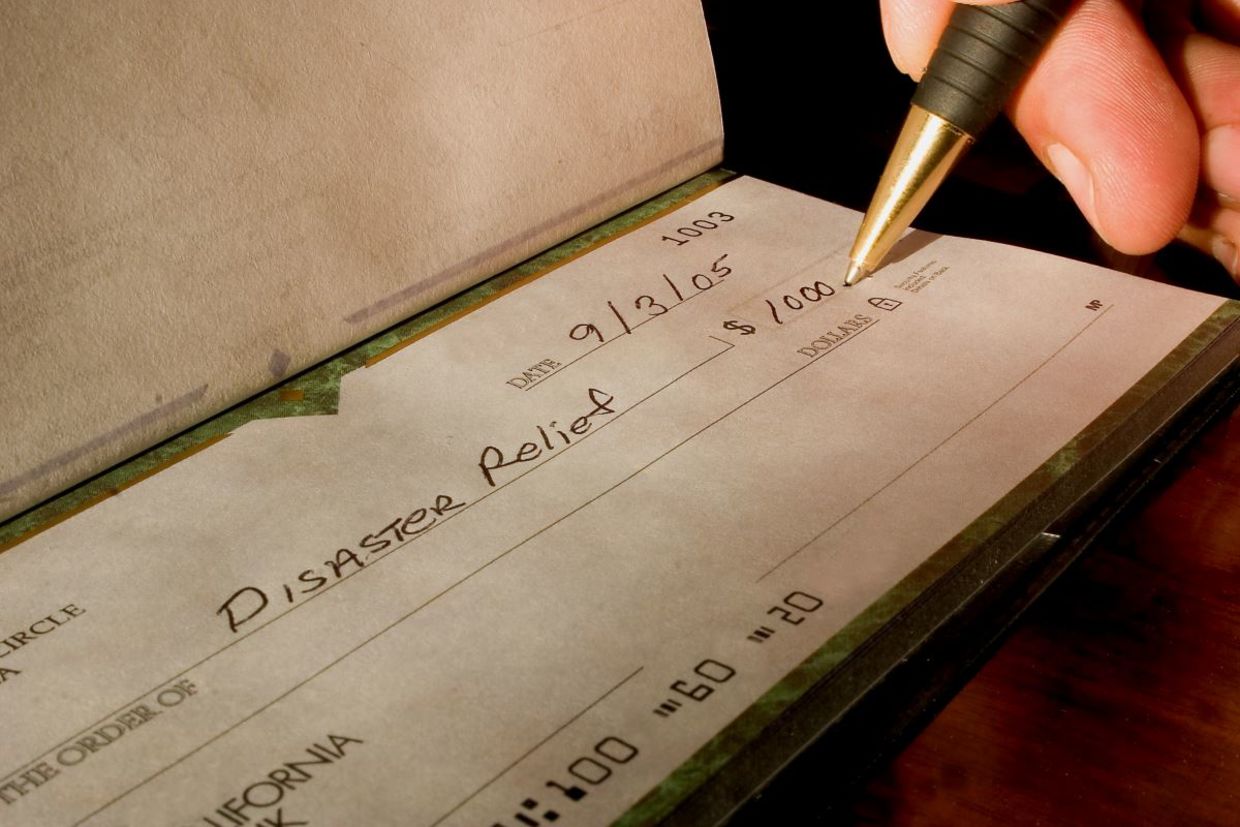 Writing a donation check. Writing a donation check.