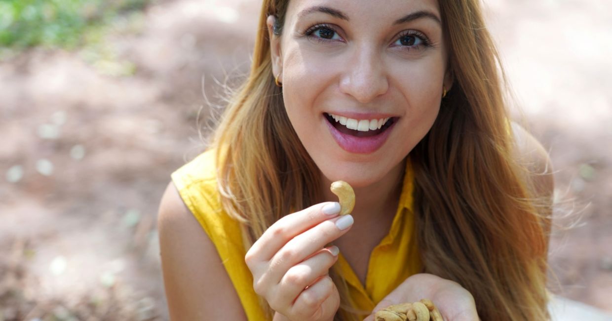 Young woman enjoying cashew nuts. Young woman enjoying cashew nuts.