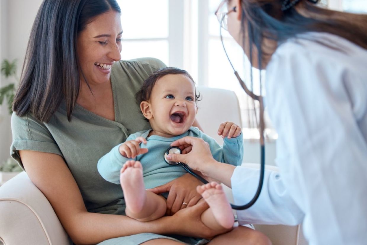 A baby smiles during a medical checkup. A baby smiles during a medical checkup.