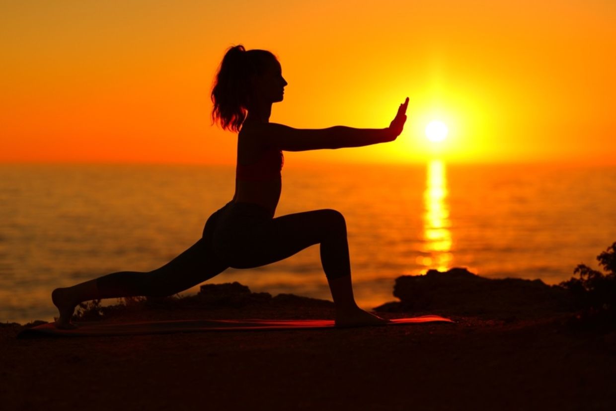 A woman does Tai Chi at sunset on the beach. A woman does Tai Chi at sunset on the beach.