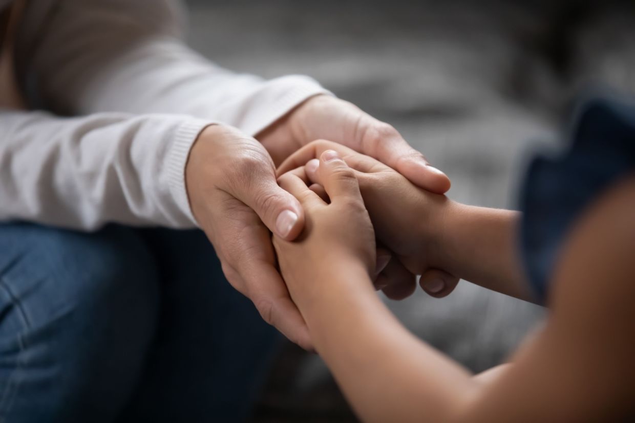 An adult and a child hold hands. An adult and a child hold hands.