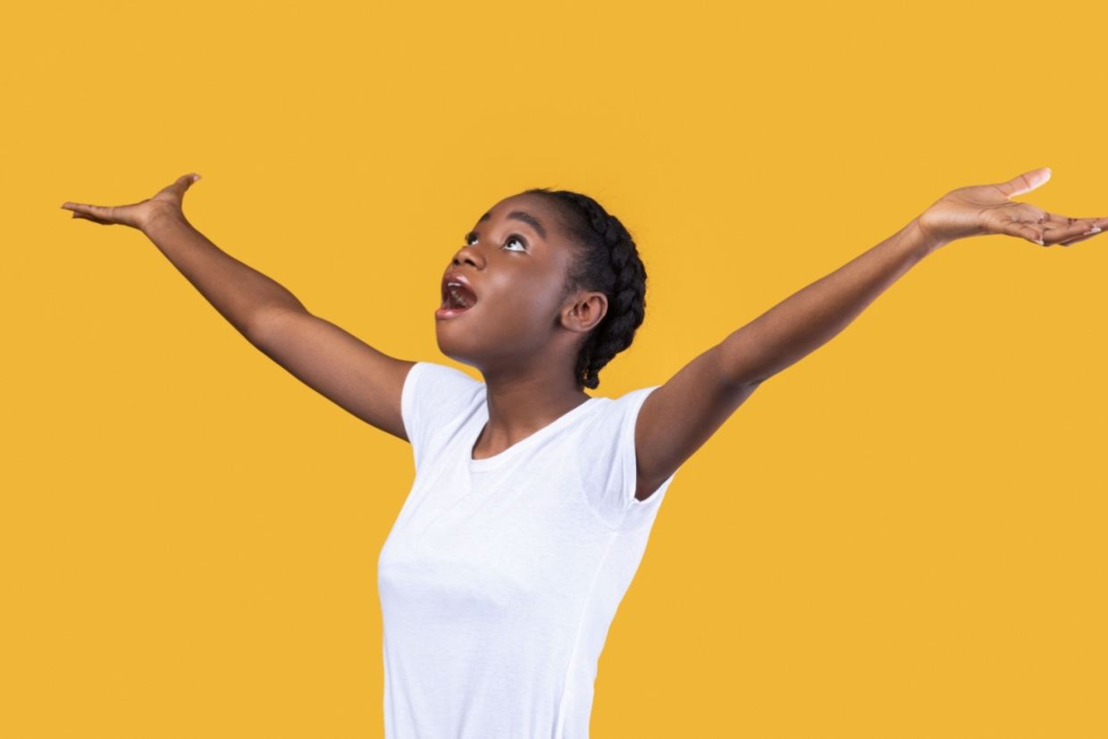 An amazed woman looks up with her hands raised. An amazed woman looks up with her hands raised.