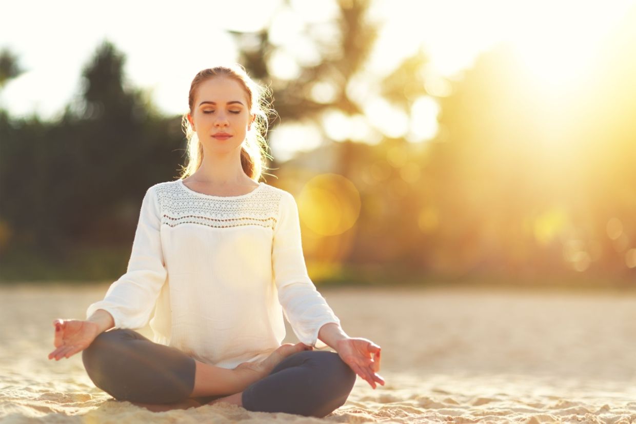 A woman practices yoga and meditates on the beach. A woman practices yoga and meditates on the beach.