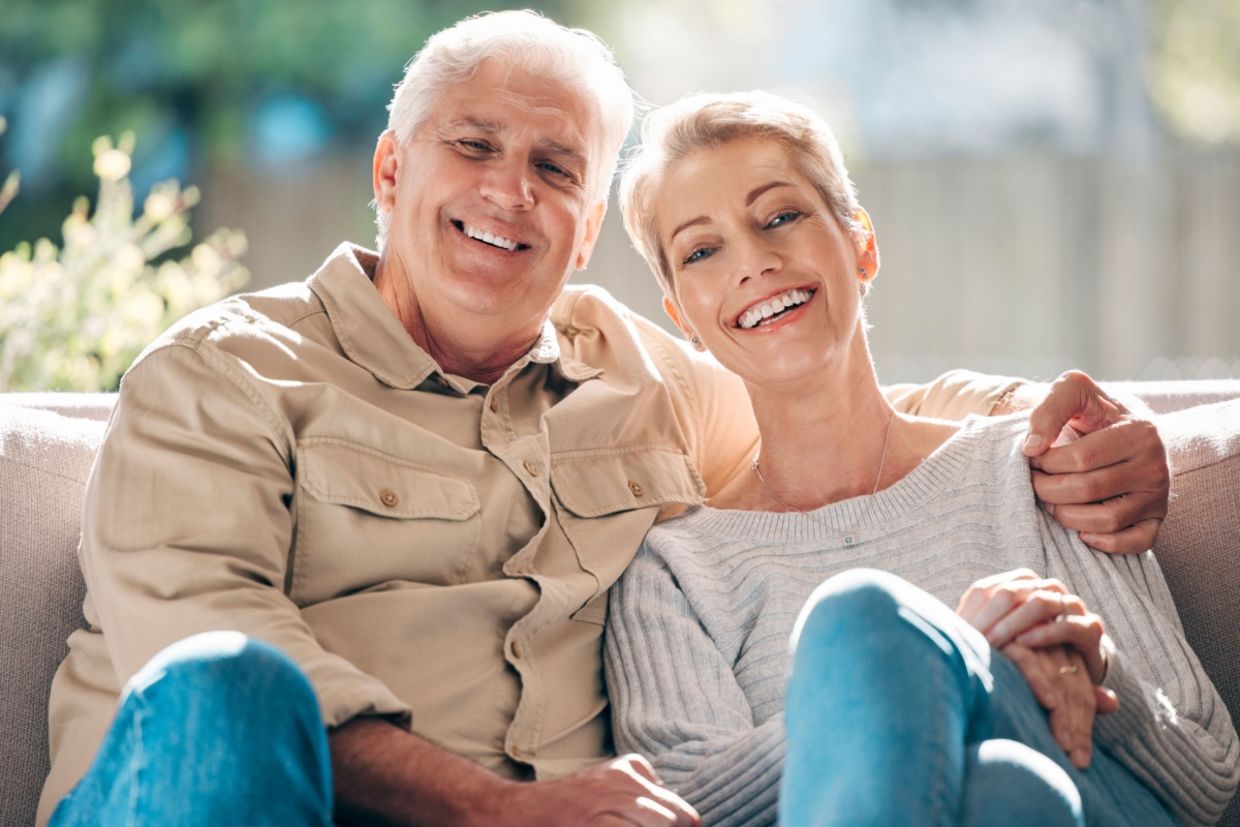 A senior couple sits on a couch. A senior couple sits on a couch.