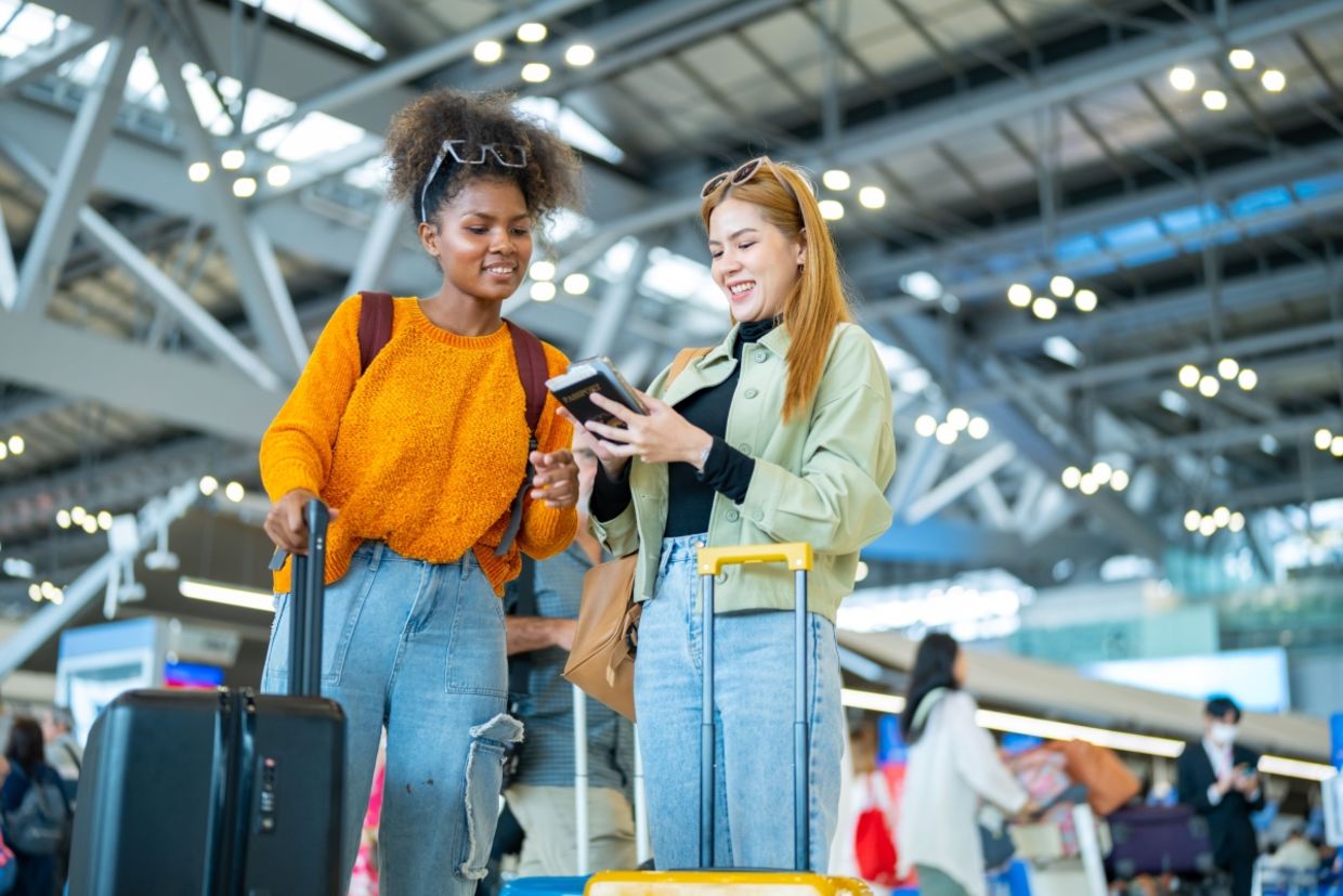 Two women stand in an airport. Two women stand in an airport.