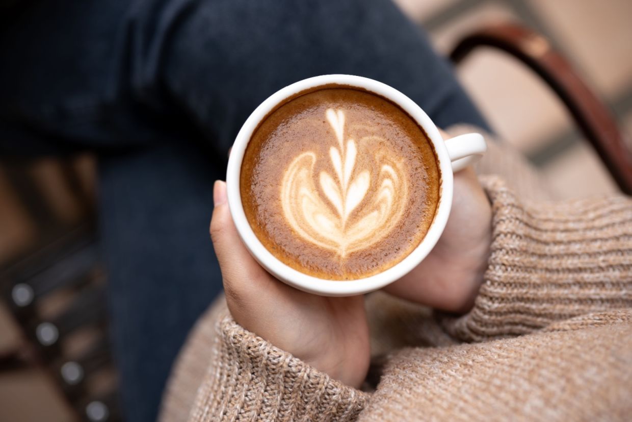A woman holds a cup of coffee.