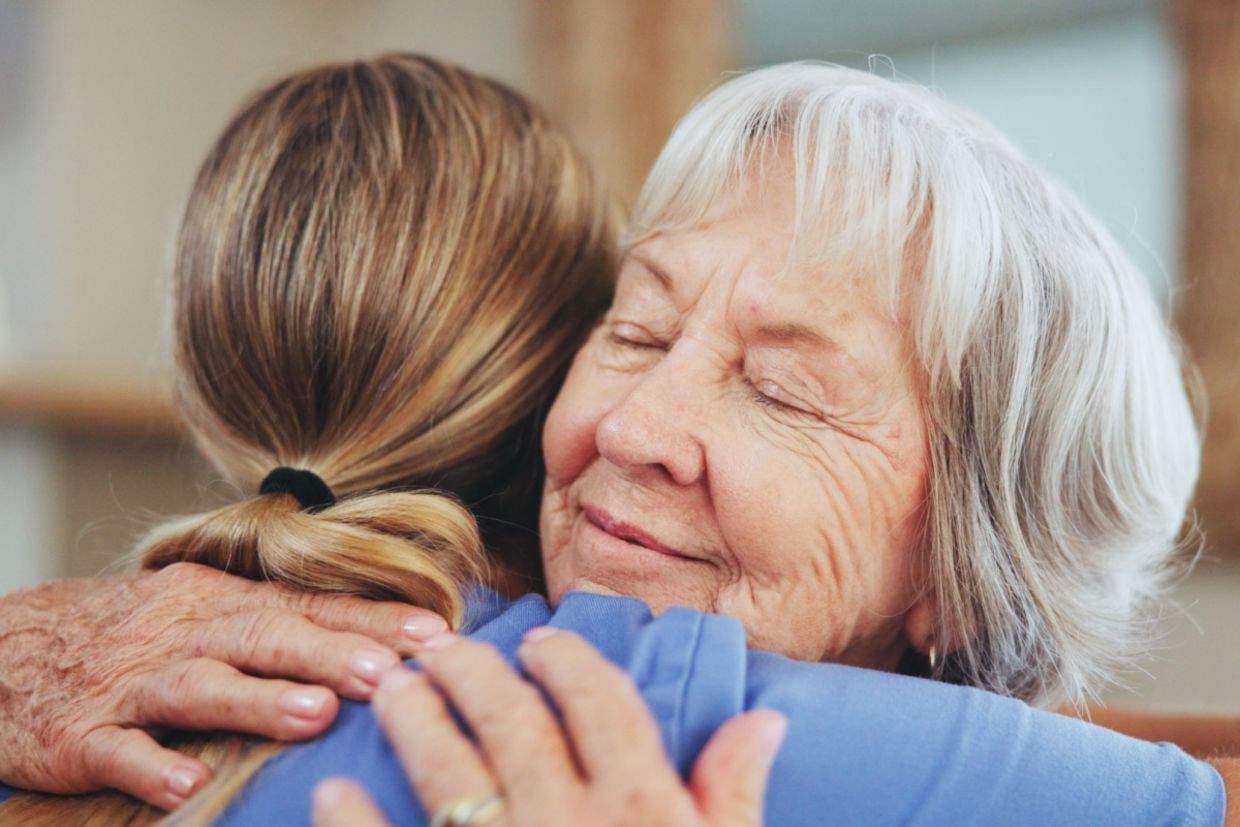 A woman hugs another woman. A woman hugs another woman.